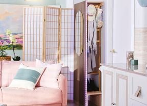 Close up of the corner of an entryway with a compact cloakroom/mudroom at the entrance, a free-standing divider, and a pale pink lounge