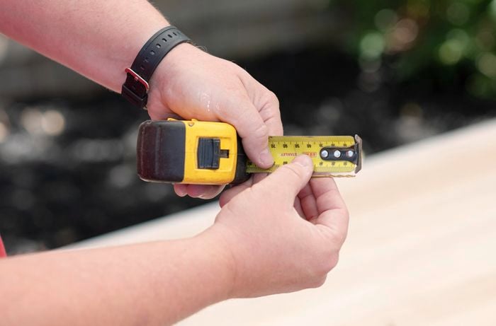 A Bunnings team member measuring the depth of a piece of timber with measuring tape