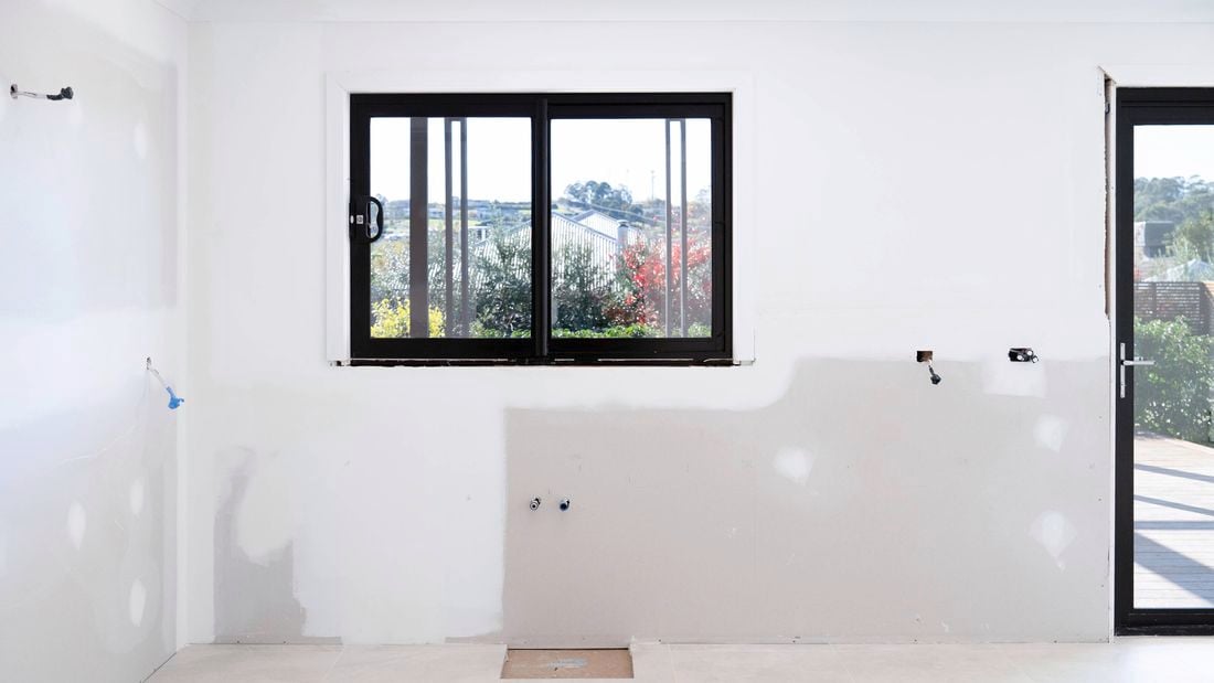 A kitchen with fresh white walls and exposed fittings, ready for a budget makeover using flat-pack cabinetry, affordable materials, and smart planning.