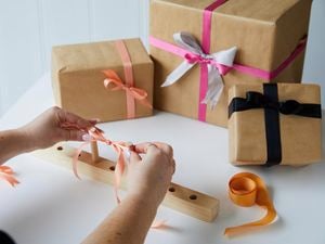 Person with a finished bow made using the bow maker and gift boxes with bows. 
