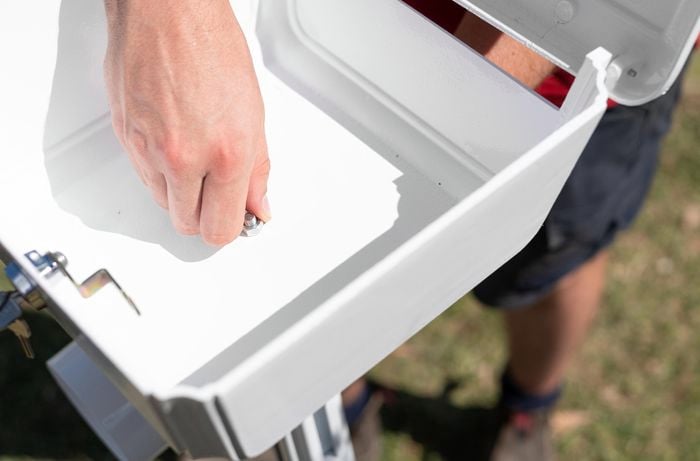 A person assembling a letterbox outdoors