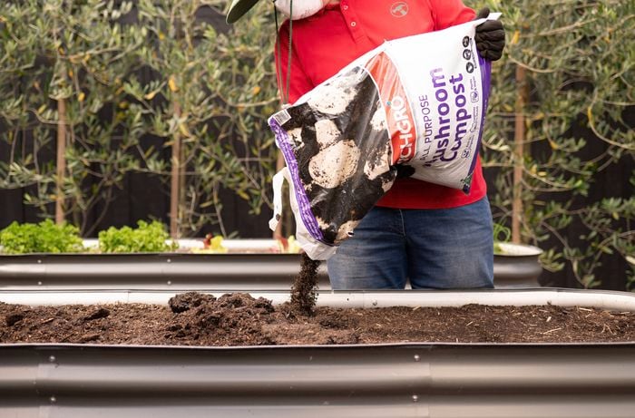 A Bunnings team member is adding Richgro all purpose mushroom compost