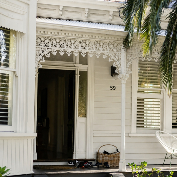 White-painted home exterior with decorative timber fretwork, shutters and a shaded verandah finished in Taubmans white paint.