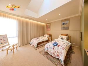 Olive and cream kids bedroom with twin beds and animal print linen, 2 coloured rugs and a kids whiteboard and seat in the corner.