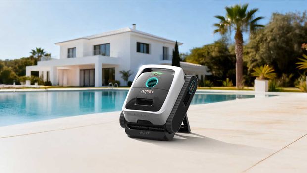 A robotic pool cleaner sitting beside a pool with a modern white house in the background.