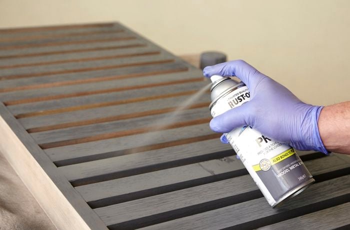 Person applying undercoat layer to table using spray paint