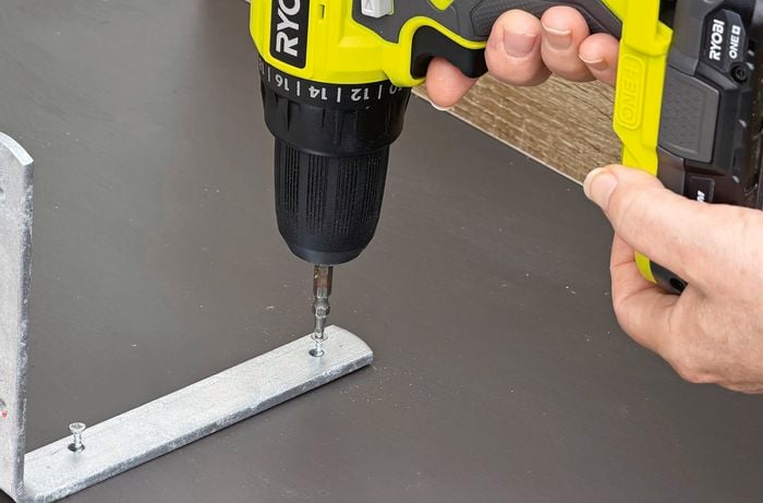 A Ryobi drill drives screws into a metal bracket.