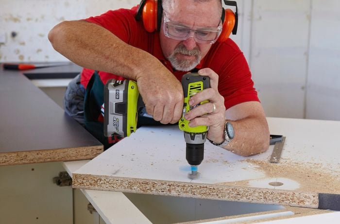 A Bunnings team member drilling into particle board