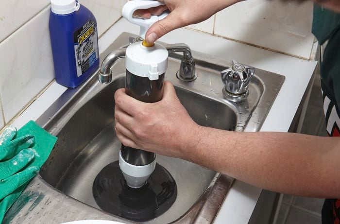 A plunger being used to unblock a drain