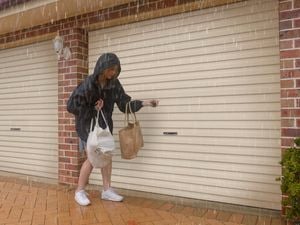 A woman in the rain opening a garage door