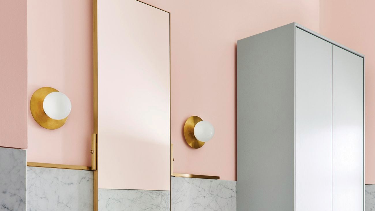 Bathroom with grey marble and pink wall, rectangular mirror above a white sink with storage cabinets to the right]
