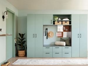 Person sitting on teal cupboard untying shoes with woven storage box placed over head