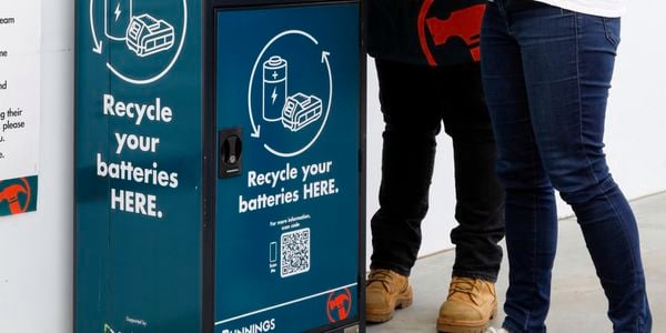 team member and customer using battery recycling bin