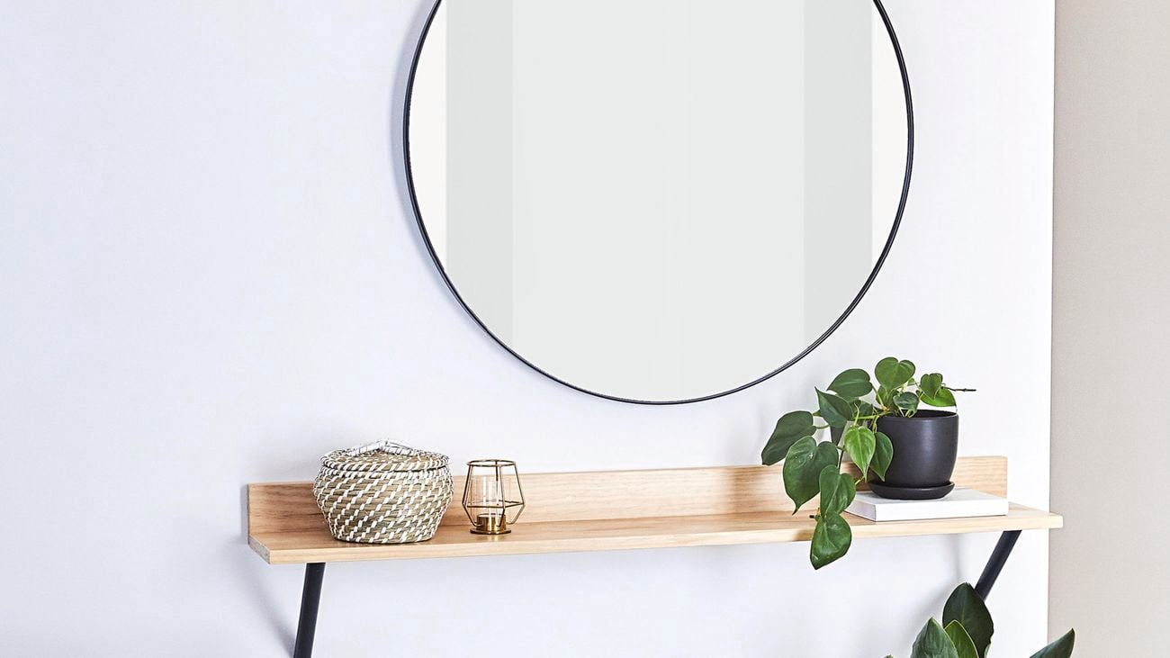 A wooden shelf with a candle and indoor plant.
