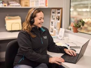 lady sitting at a desk with head phones on while using her laptop