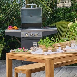 Backyard outdoor dining setting with a jumbuck BBQ in the background