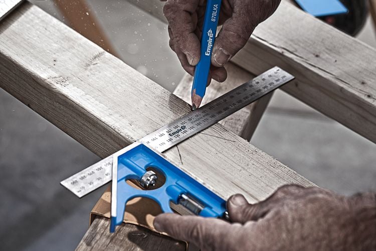 A piece of timber being marked for cutting using a pencil and square rule