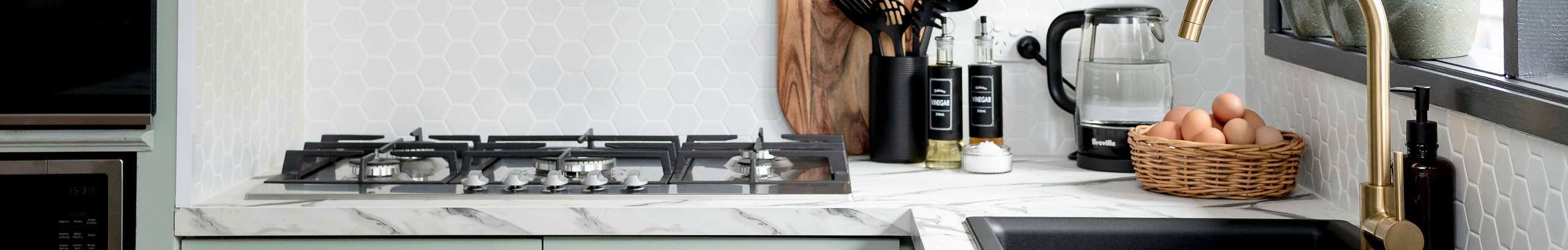 Kitchen with green cabinets and marble benchtops.