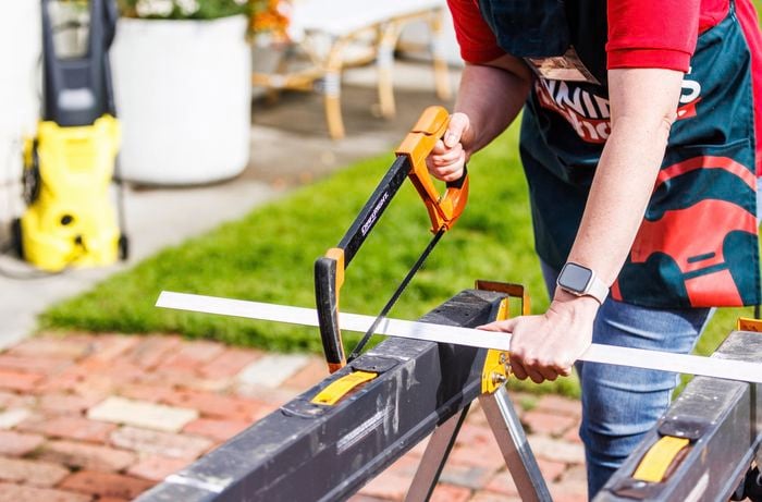 A person cutting an aluminium using a hand saw.