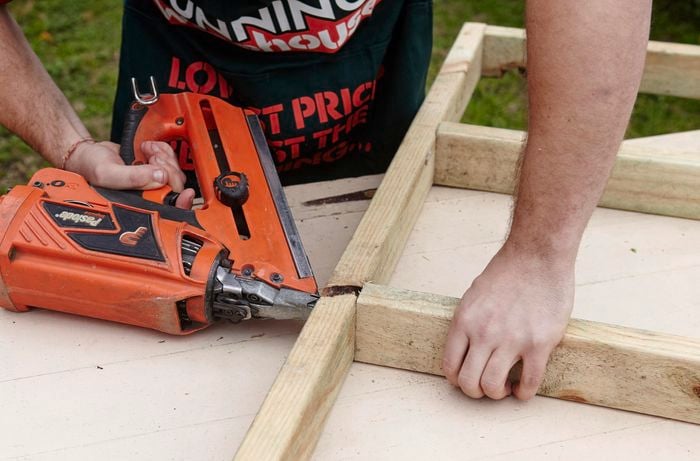 A wooden frame being assembled on a workbench by a Bunnings team member with a nail gun as part of a chicken coop
