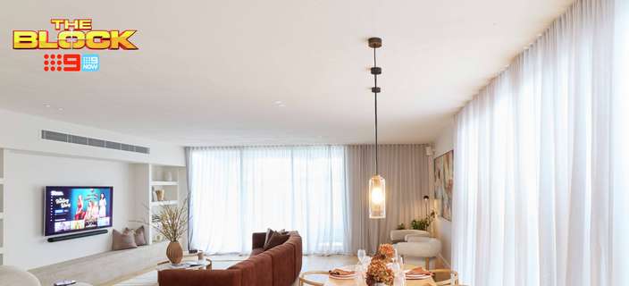Open-plan living and dining area featuring a timber dining table, brown sofa, pendant lighting and floor-to-ceiling sheer curtains.