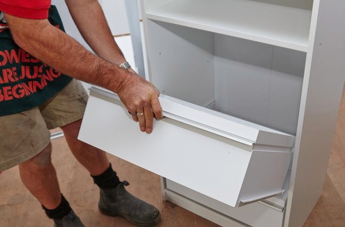Person sliding drawer into the rest of the wardrobe unit.
