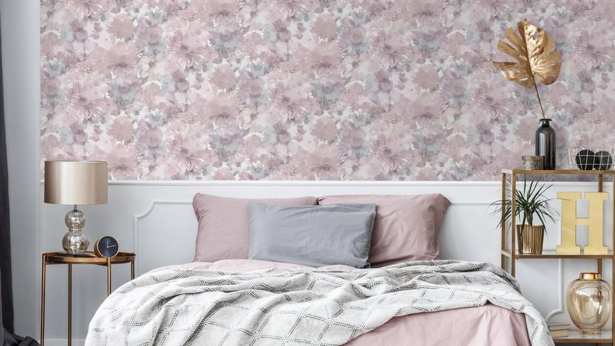 Bedroom with floral pastel wallpaper, bed with light coloured furnishings and side tables with accessories.