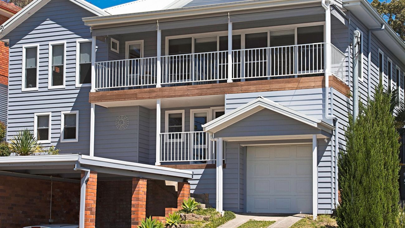 Front exterior of a Hamptons-style two-storey house renovated with cladding.
