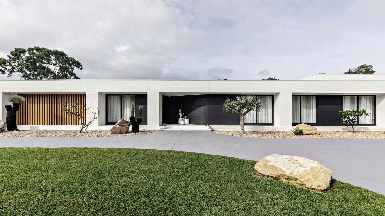 House that is white and tiled with concrete driveway