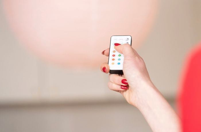 Person controlling a rechargeable LED light bulb with a remote
