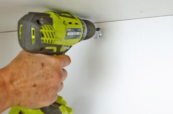 Person screwing brackets into inside of cabinet
