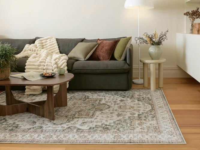 Modern lounge with sofa, patterned rug, coffee table, and floor lamp