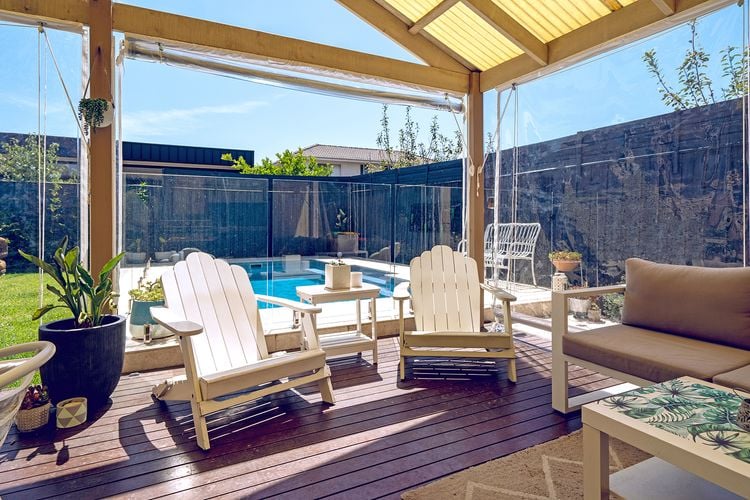 Covered outdoor timber decking area with white timber chairs