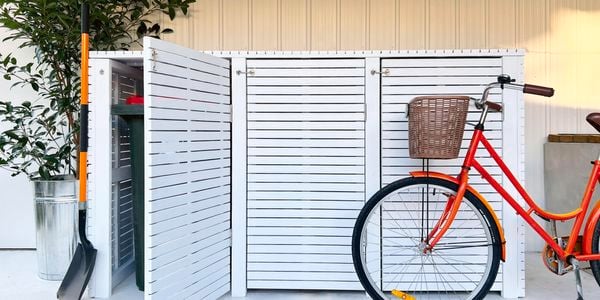 Three door bin screen with shovel in front of half-opened one bin screen and bicycle on other side. 