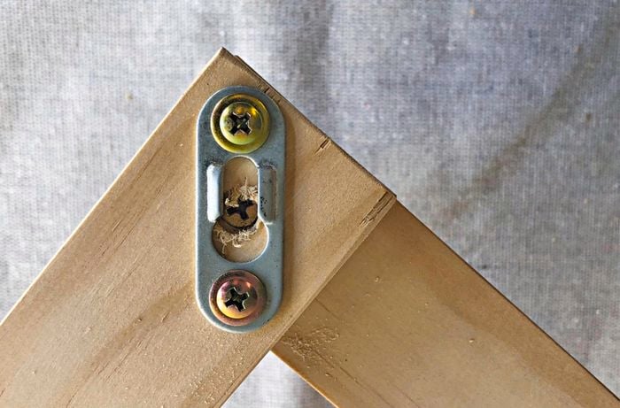 A metal keyhole plate attached to a timber frame with screws