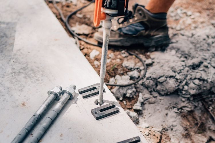 Person inserting Ramset adhesive into a hole in a concrete slab