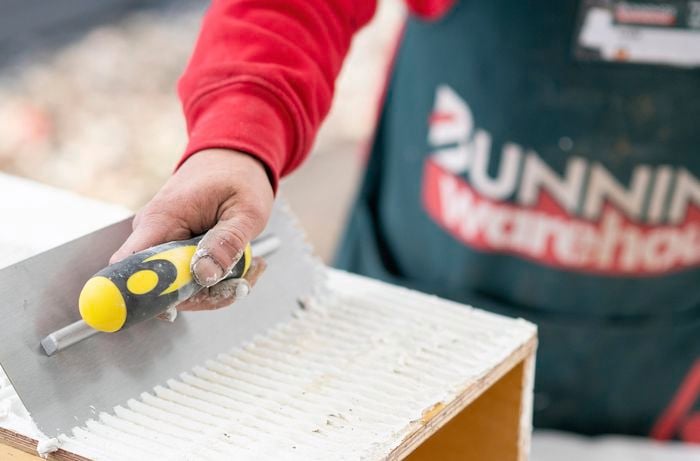 Tile adhesive being applied to the surfaces of a wooden table
