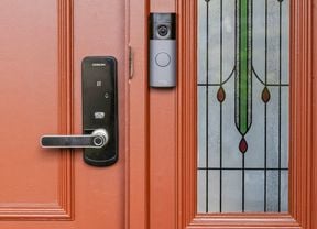 Smart door lock and Ring video doorbell installed on a red front door with decorative glass panel