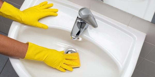 Pair of hands cleaning a sink with Jif cleaning products
