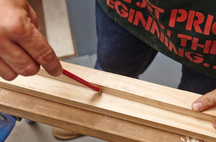 A person marking an angled line on a length of timber