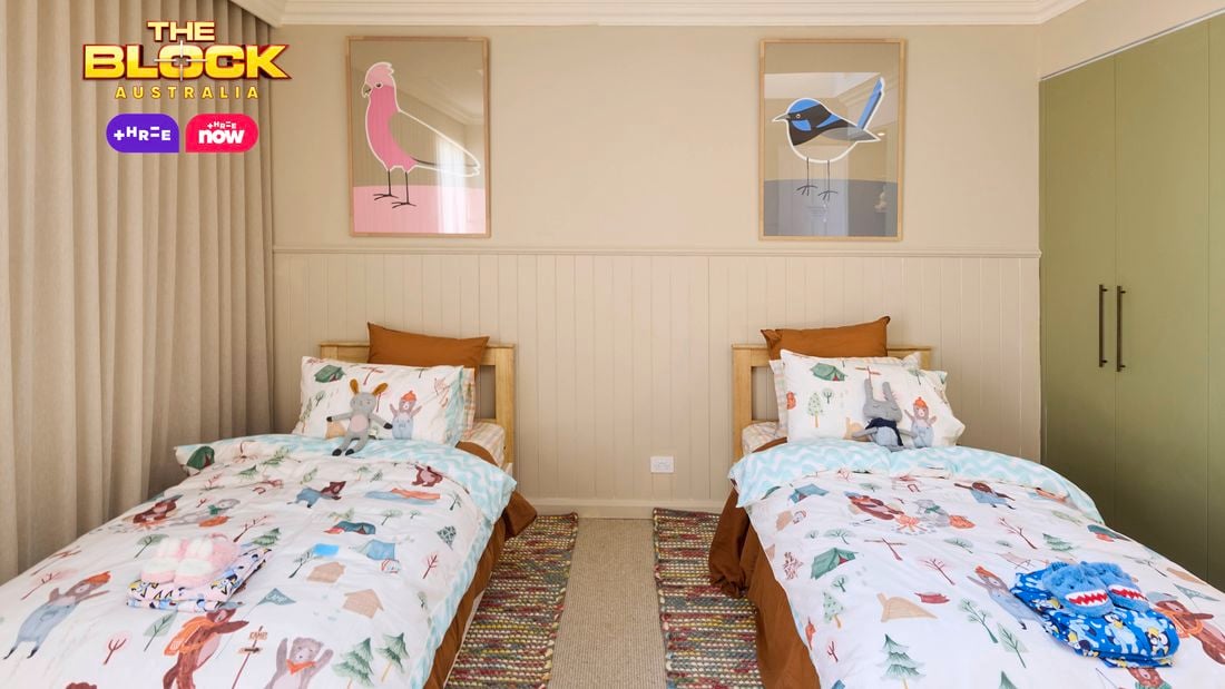 Olive and cream kids bedroom with twin beds and animal print linen, 2 coloured rugs and a wardrobe and desk on the opposite wall.
