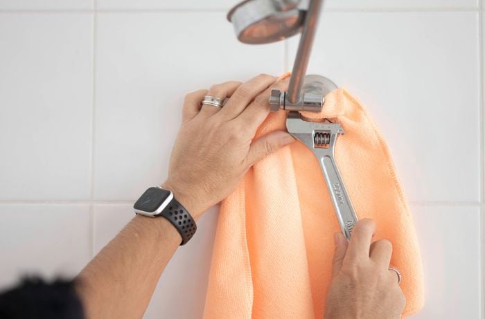 Using a shifter to grip the base of the old shower head.