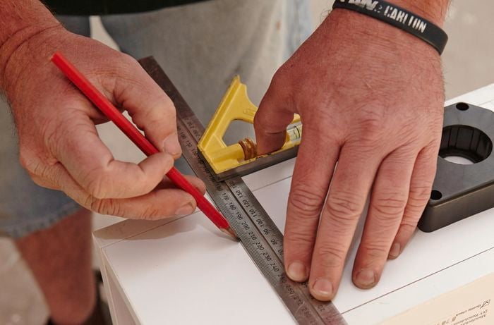 Person measuring and marking position for feet on bottom of wine rack