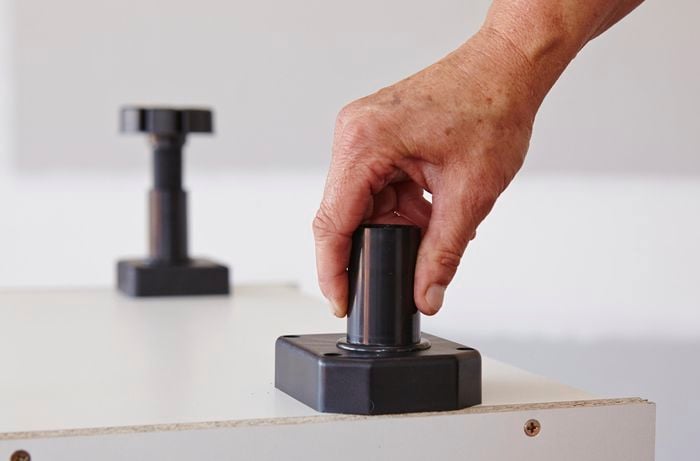 Plastic feet being attached to an oven cabinet