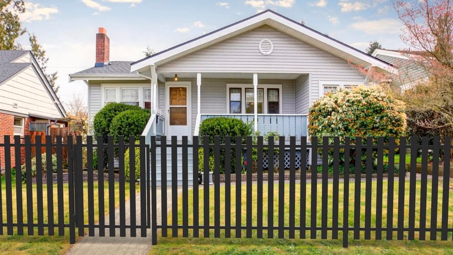 Front of a cottage house with front garden and fencing.