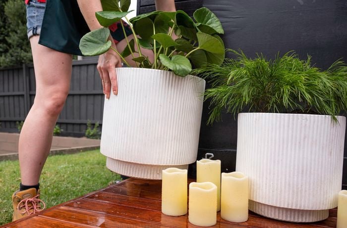 A Bunnings team member positioning a large white planter on a wooden deck