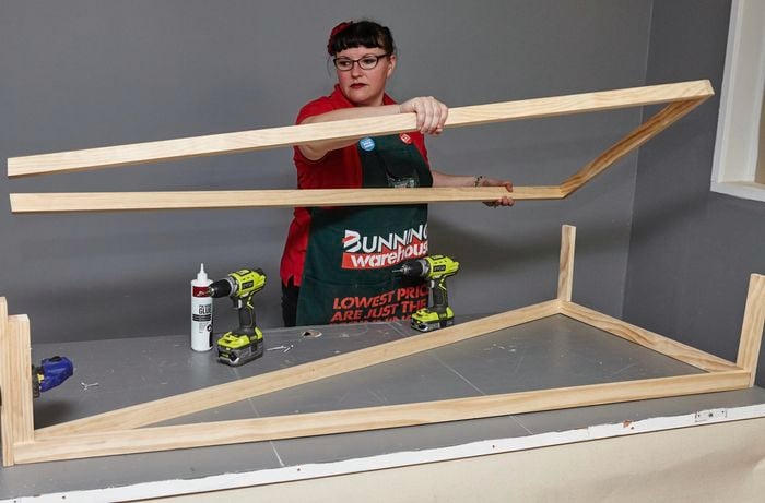 Person assembling one side of DIY industrial wooden bookshelf.