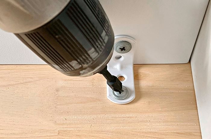 Angle brackets drilled into a kitchen trolley top and frame.