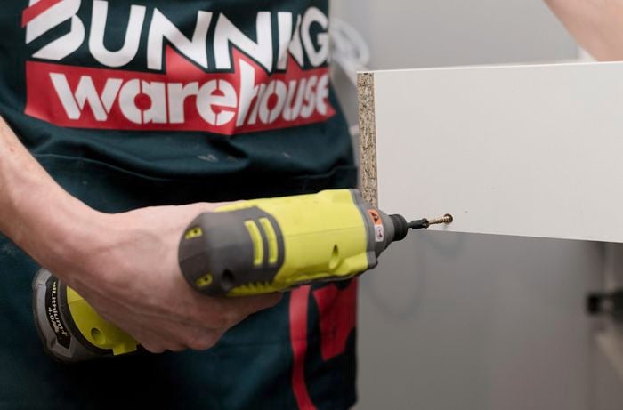 Using a drill to screw in screws.
