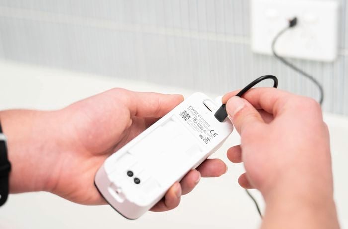 A person is charging the wireless video doorbell with the USB-C cable.  